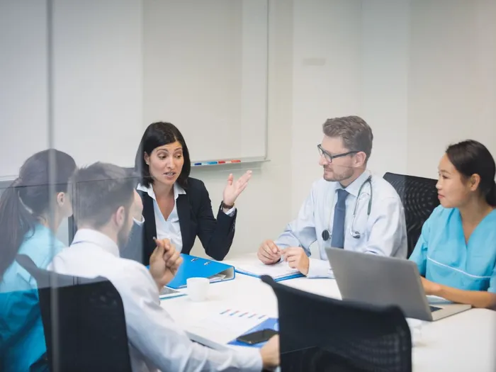 A team of healthcare and business professionals in a meeting around a boardroom table